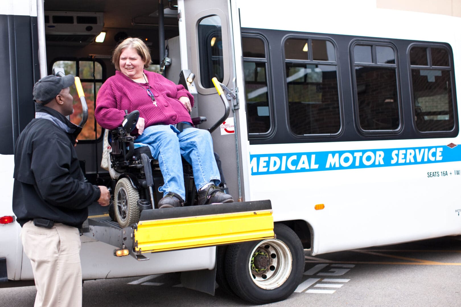 A woman in a wheelchair is sitting on the back of a bus.