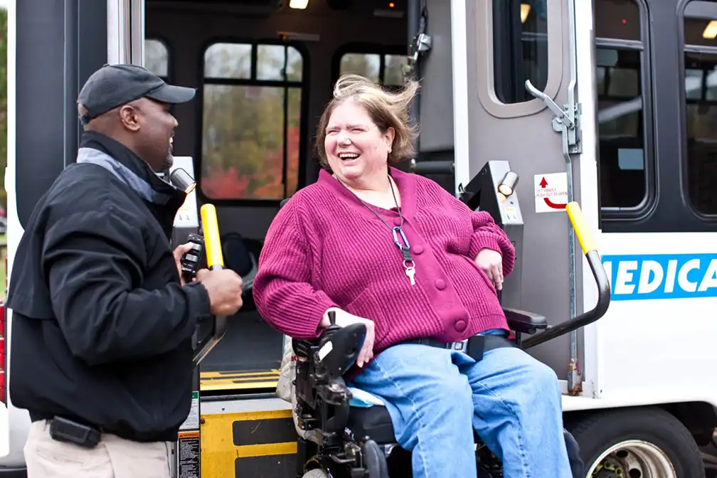 A woman in a wheelchair is sitting on the back of a bus.