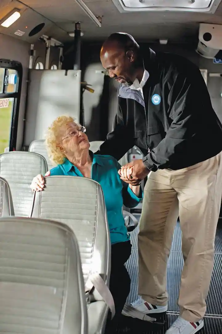 photo of MMSNYS driver assisting elderly woman seated in bus
