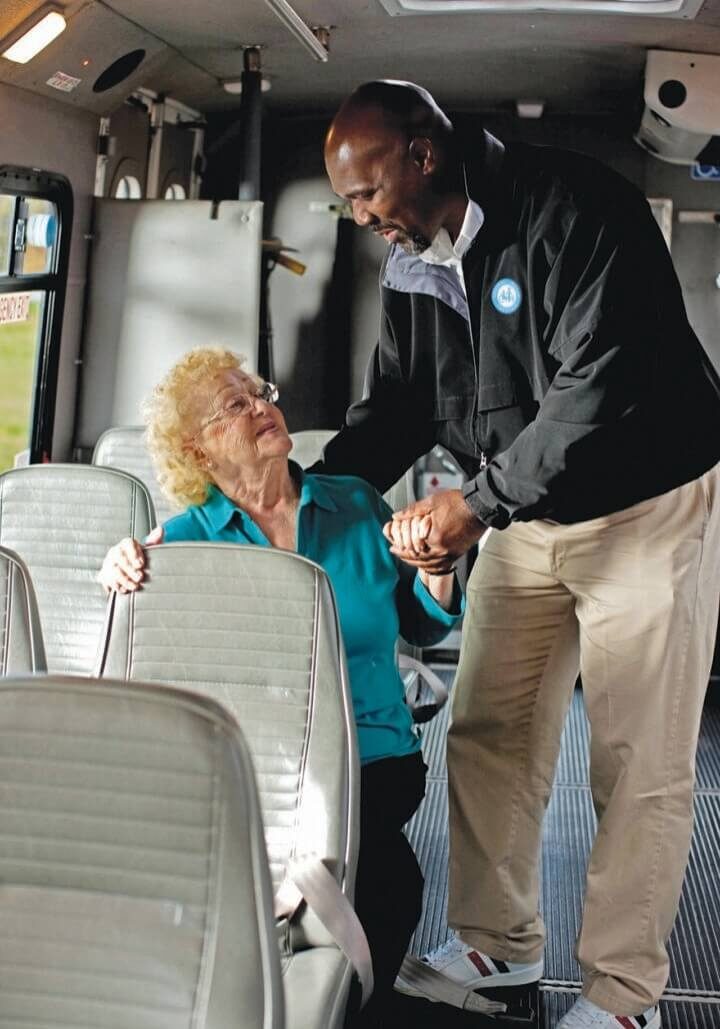 A man and woman on a bus talking to each other.